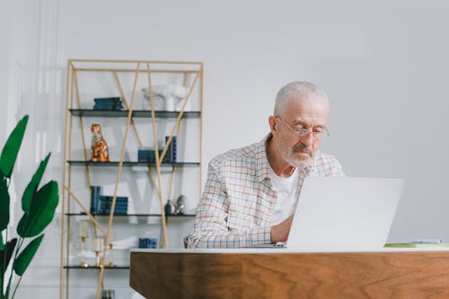 Free An Elderly Man with Eyeglasses Sitting while Using a Laptop Stock Photo