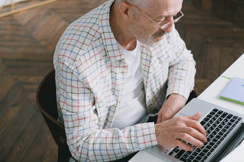 Free Close-Up Shot of an Elderly Man with Eyeglasses Sitting while Using a Laptop Stock Photo