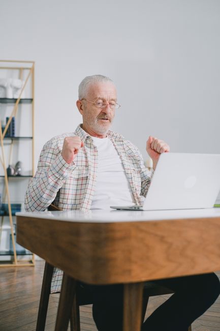 Elderly man at a laptop reviewing his retirement finances at home.