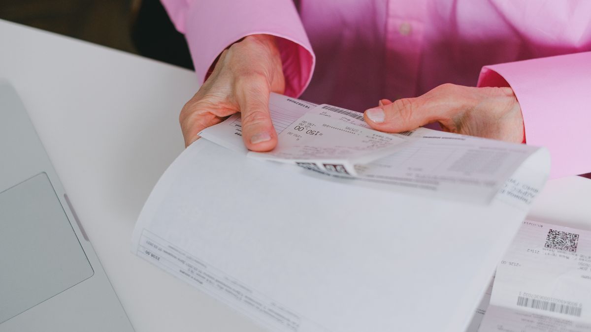 Business person handling paper receipts, meticulously organized.