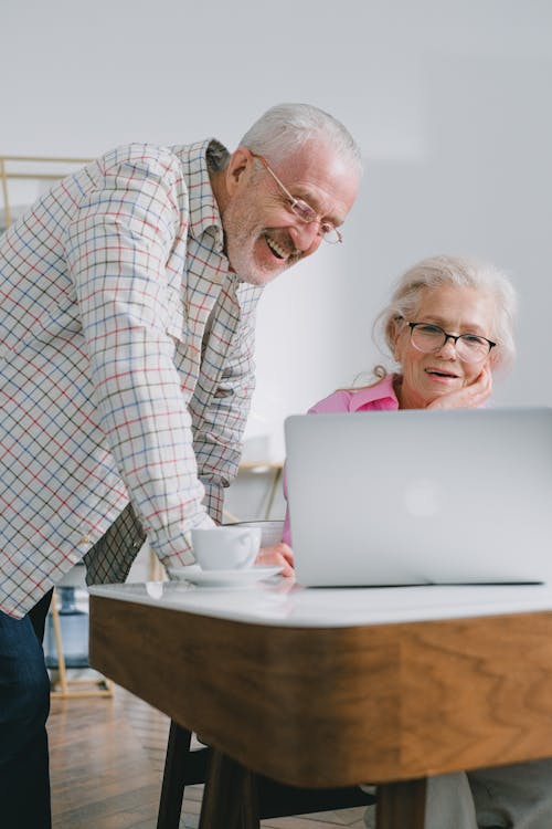 Free An Elderly Man and Woman Smiling while Looking at Laptop Stock Photo