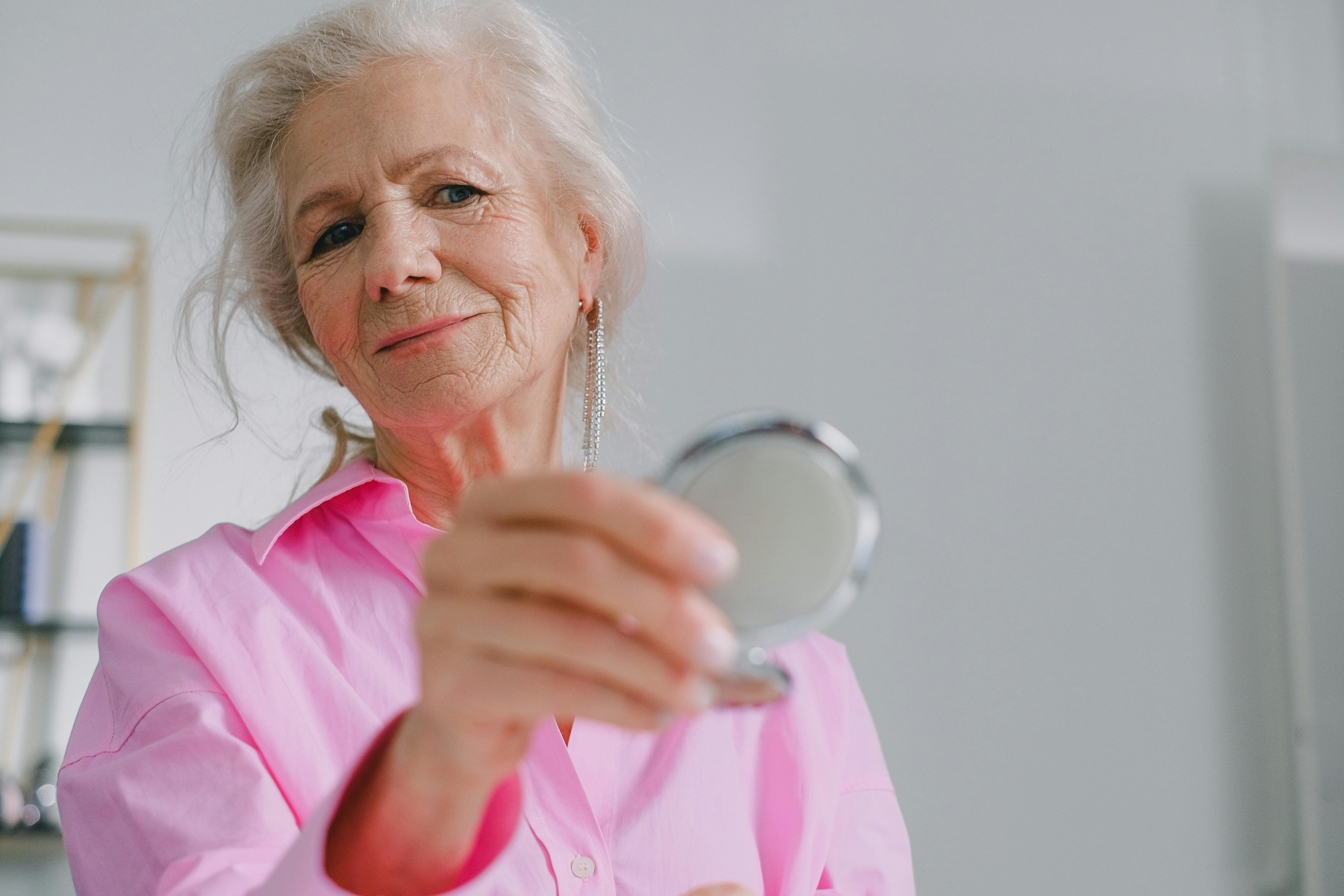 an elderly woman holding a mirror