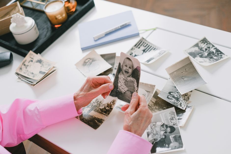 A neat flat lay of printed family photos spread on a table, hands sorting them into labeled stacks. 📸: SHVETS production