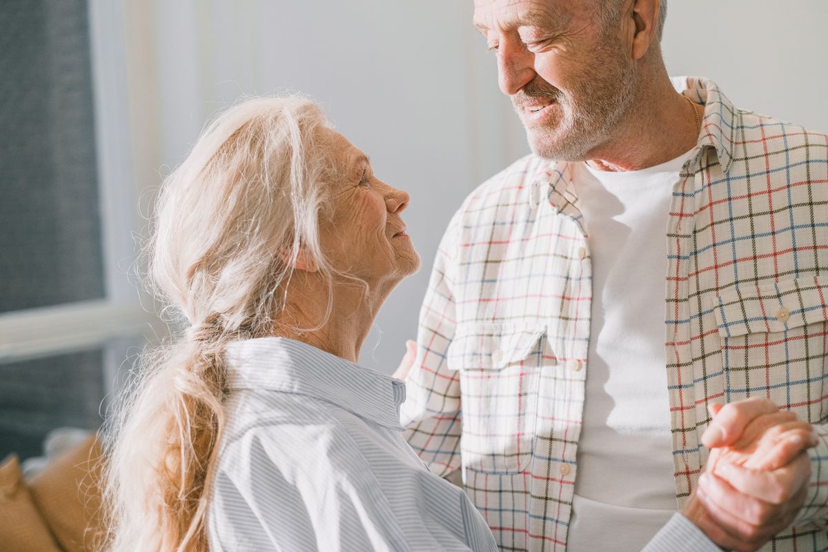 Older couple smiling and holding hands at home