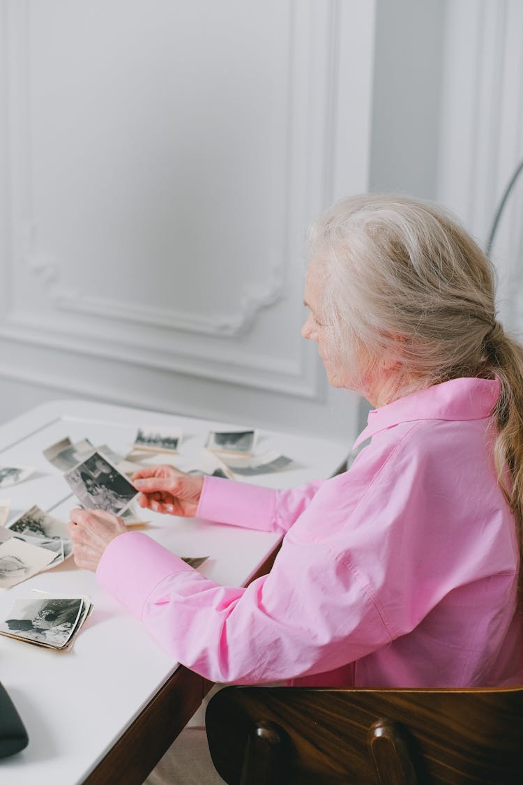 Elderly Woman Looking Through Old Black And White Photographs 