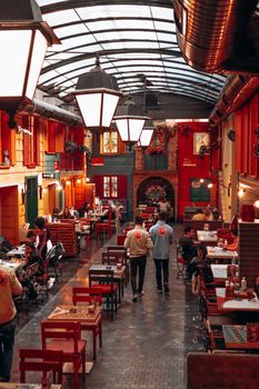 Lively pub interior with colorful decor, people dining under warm lighting, creating a cozy atmosphere.
