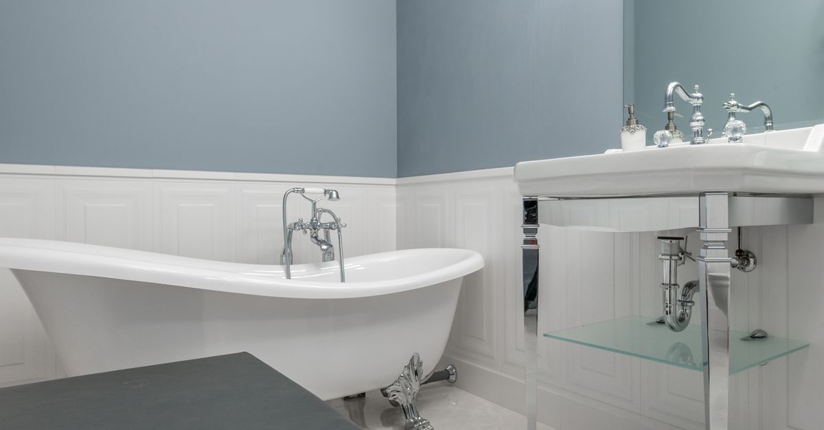 Interior of stylish bathroom with empty white bathtub and sink in luxury modern flat