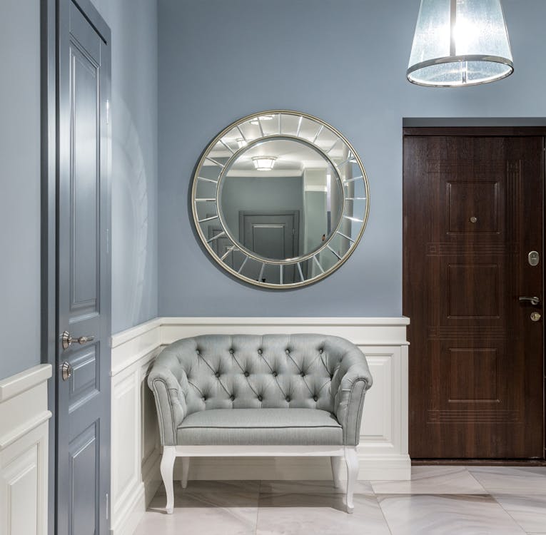 Free Gray leather armchair placed under stylish round mirror in light corridor with gray walls in contemporary apartment in daytime Stock Photo