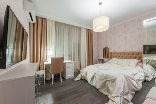 Free Large comfortable bed with light linen placed in front of TV in stylish bedroom with pink walls in modern apartment Stock Photo