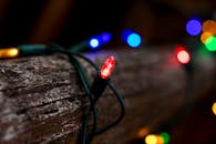 彩色串灯的特写镜头缠绕在木头上，营造出舒适喜庆的氛围