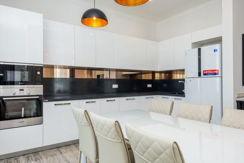 Free A clean, modern kitchen with white cabinets and a dining area. Stock Photo