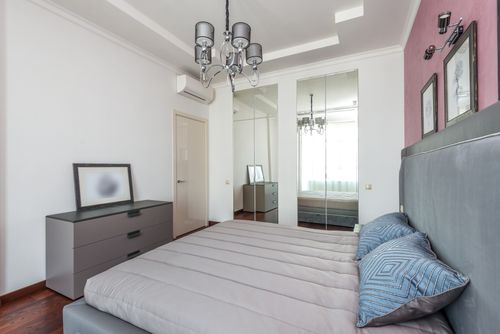 Free Bright contemporary bedroom featuring stylish decor and mirrored closet. Stock Photo