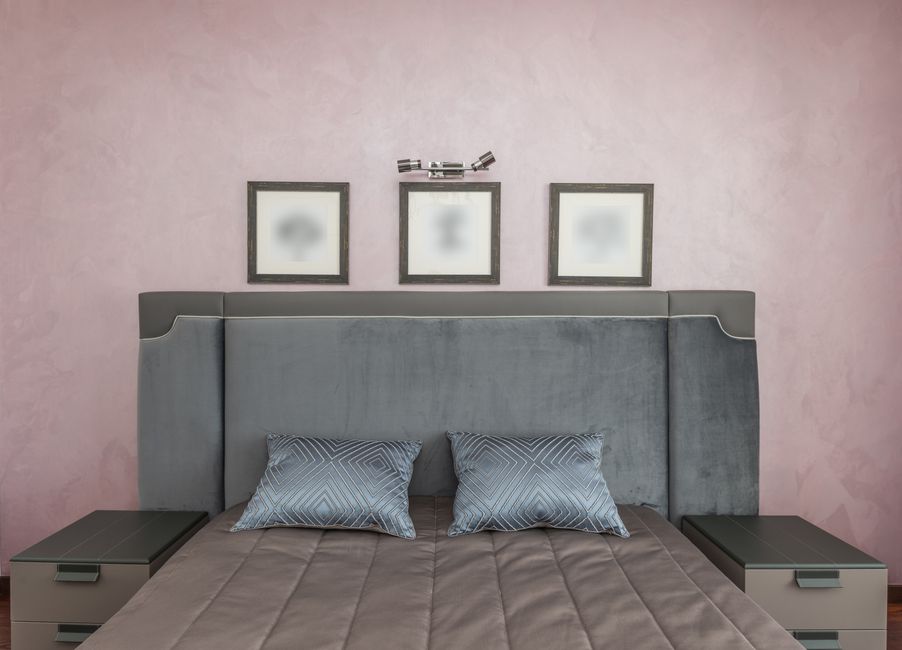 Schlafzimmer mit matter Kopfteil-Zone hinter dem Bett, hellgraue Wand und Holzdetails, abwischbare Oberfläche