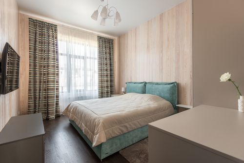 Free A serene minimalist bedroom with aqua bedding and striped curtains, featuring a cozy bed and natural light. Stock Photo