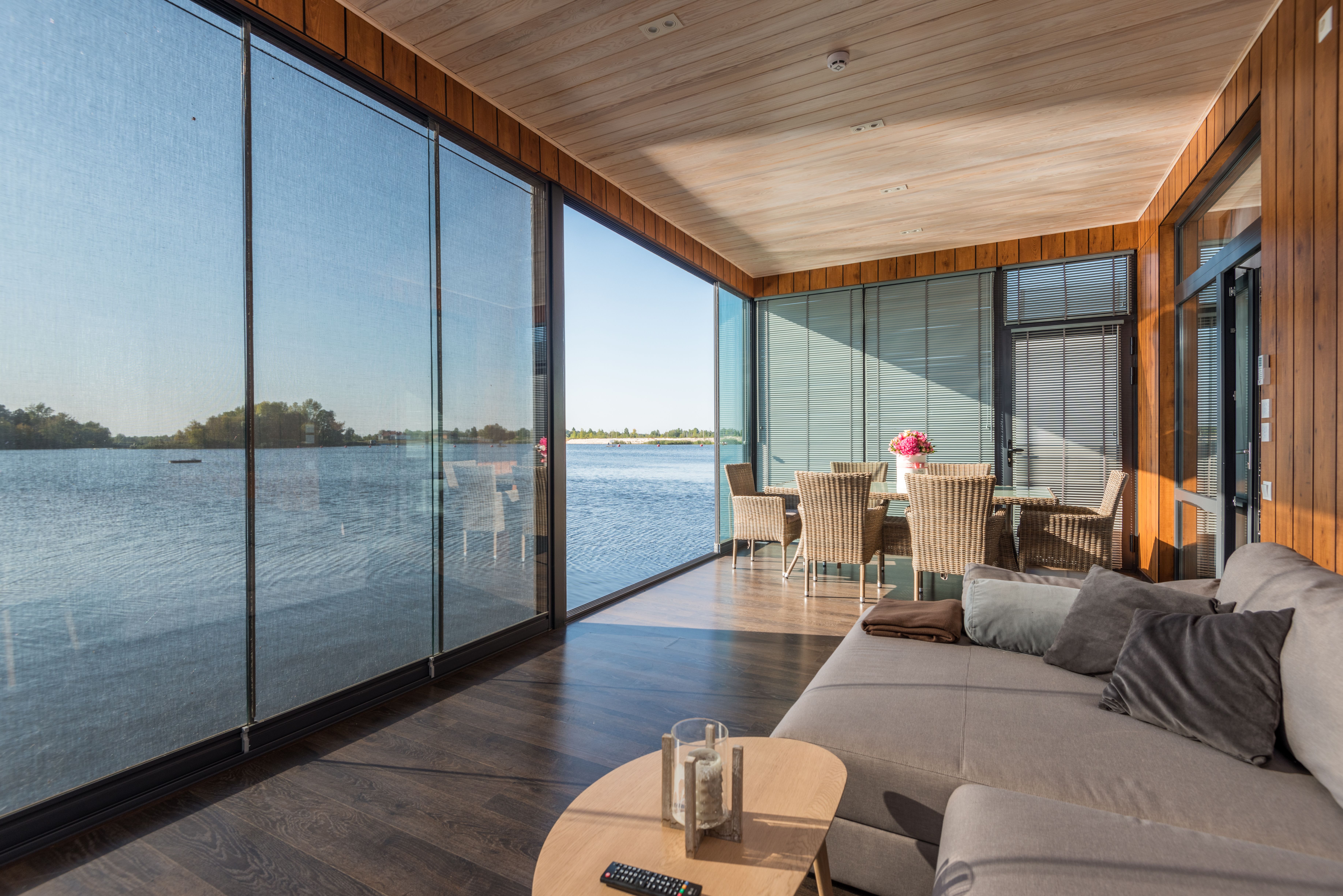 Serene living room with floor-to-ceiling glass walls opening directly onto tranquil water