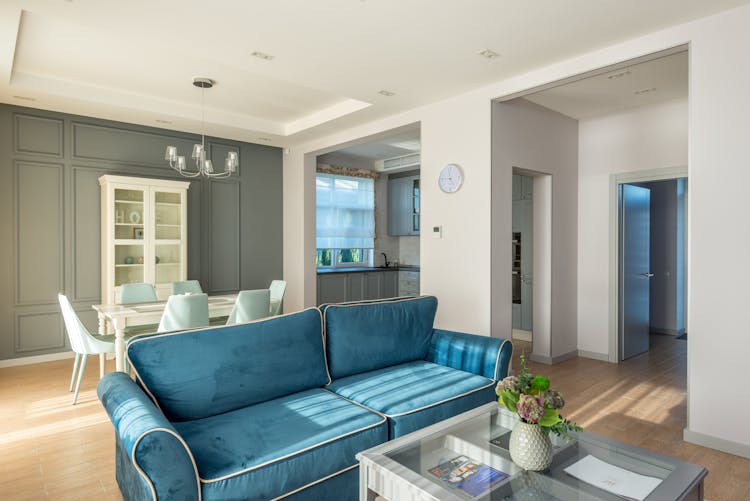 A Blue Couch Near The Dining Table With Chairs