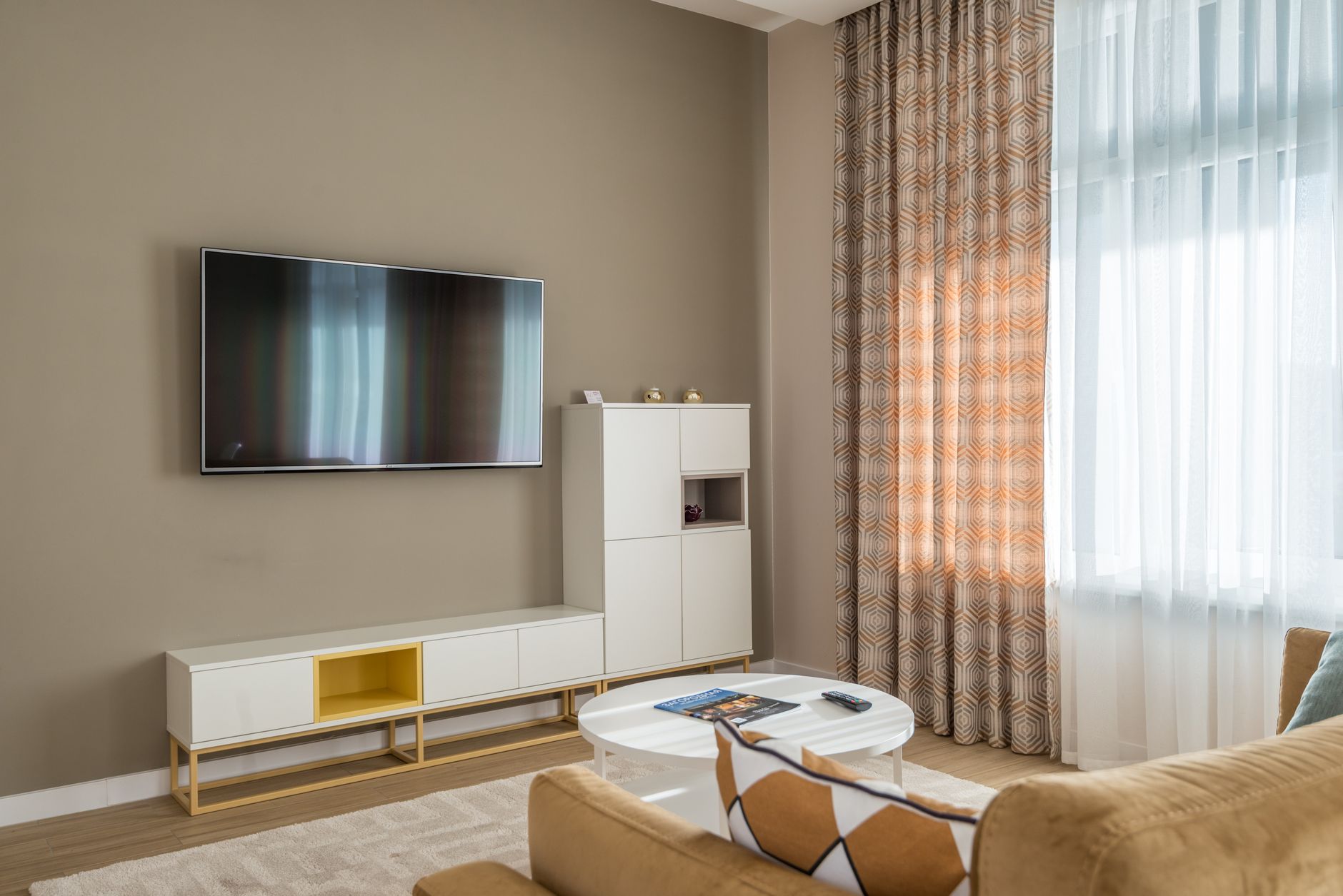 Cozy living room interior with beige walls, flat-screen TV, and stylish decor.