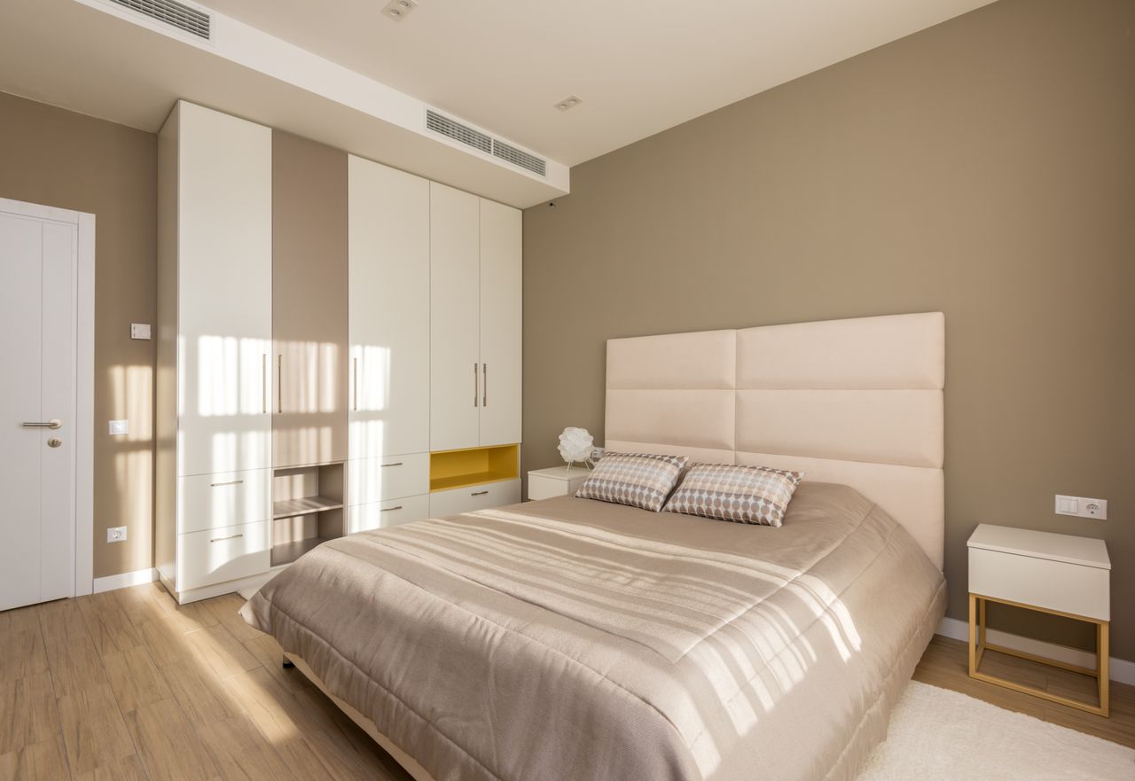 Modern bedroom with a tall white built-in wardrobe wall and mustard-yellow open shelf niche