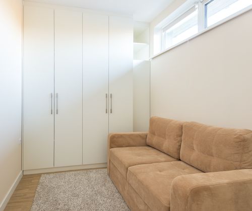 Free Bright and minimalist living room featuring a beige sofa and white cabinets. Stock Photo