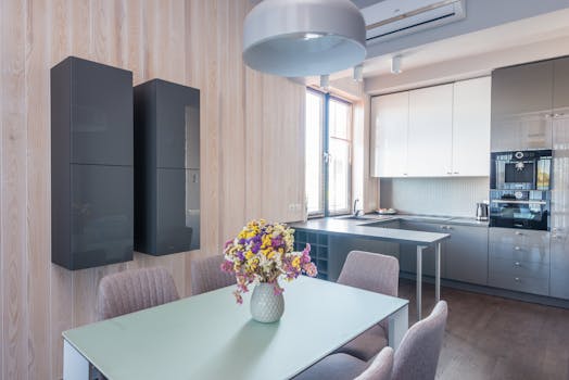 Contemporary kitchen with sleek furniture and vibrant flower vase, showcasing modern design.