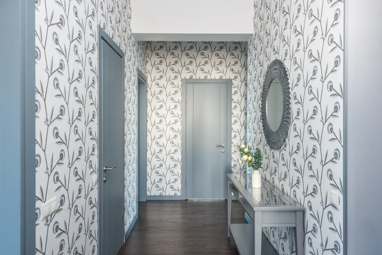 Entryway hallway with a gray console table, round mirror, and floral wallpaper