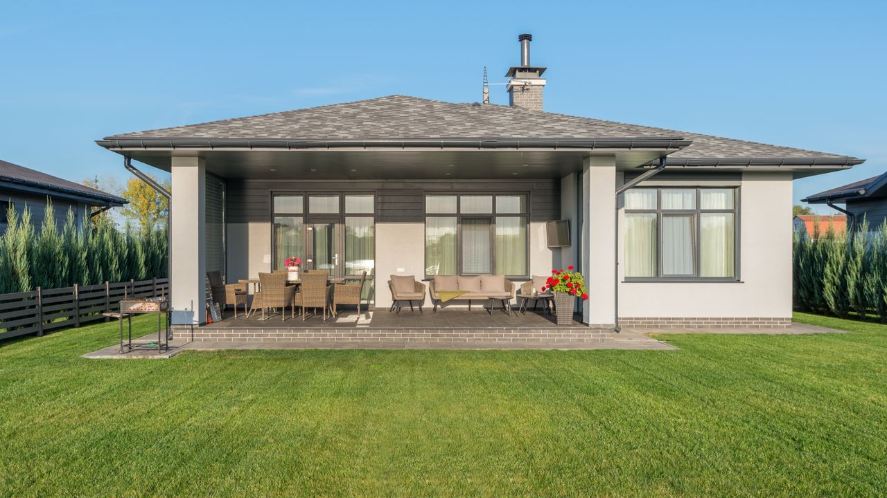 A finished back yard — cut lawn, planted border and a covered patio