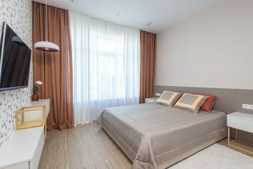 Free A contemporary bedroom with beige tones, featuring a flat-screen TV and decorative elements. Stock Photo