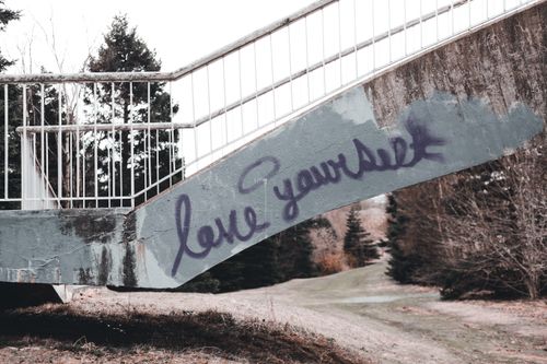 Free Stone steps with words Love yourself near metal railings above path near dry grass and leafless trees in countryside in autumn day Stock Photo