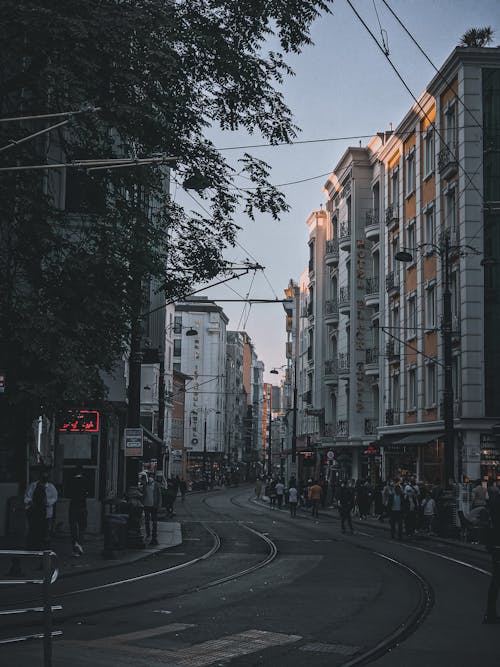 People Walking on a Sidewalk Near the Buildings