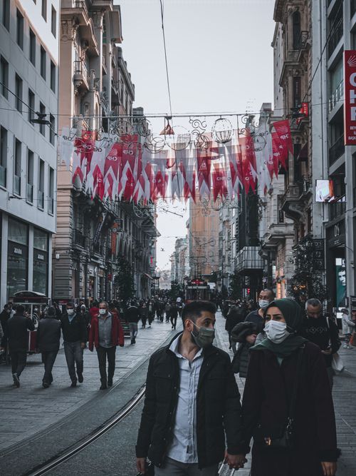 Free Beyoğlu street scene in Istanbul showing people wearing masks amid city bustle. Captures local life. Stock Photo