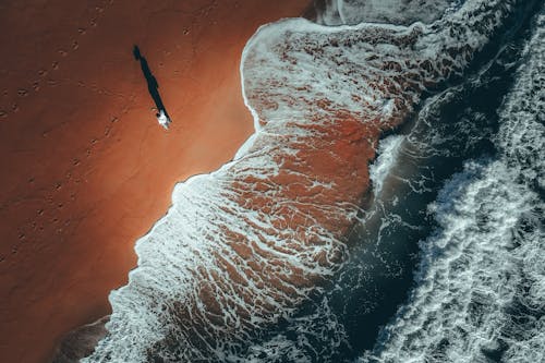 Unrecognizable traveler resting on sandy shore near waving sea