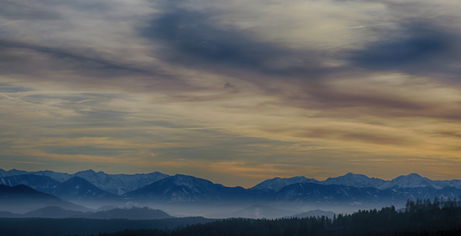 Beautiful mountain landscape in Schwambach, Austria at sunset with dramatic clouds and foggy peaks.