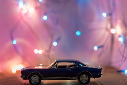 Free A miniature toy car in front of colorful festive lights creating a bokeh effect. Stock Photo