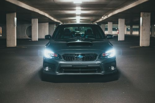 Free Gray expensive vehicle with glowing headlights parked on asphalt in underground parking lot near stone columns Stock Photo