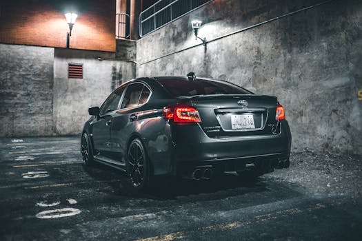 A luxury car illuminated by streetlights in a dimly lit urban parking area at night.