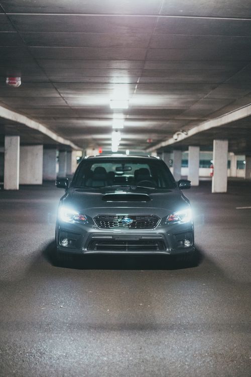 Free Gray expensive automobile with glowing headlights parked on asphalt in underground parking lot under ceiling with lamps Stock Photo