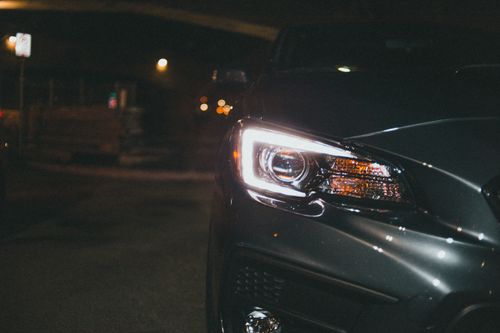 Free Close-up night shot of a car headlight illuminated, capturing its sleek design. Stock Photo