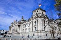 在明亮的蓝天下，柏林的国会大厦悬挂着旗帜，展示了政府建筑的风貌