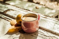 乡村桌子上放着一个粉红色的陶瓷咖啡杯，旁边有秋叶和一个苹果