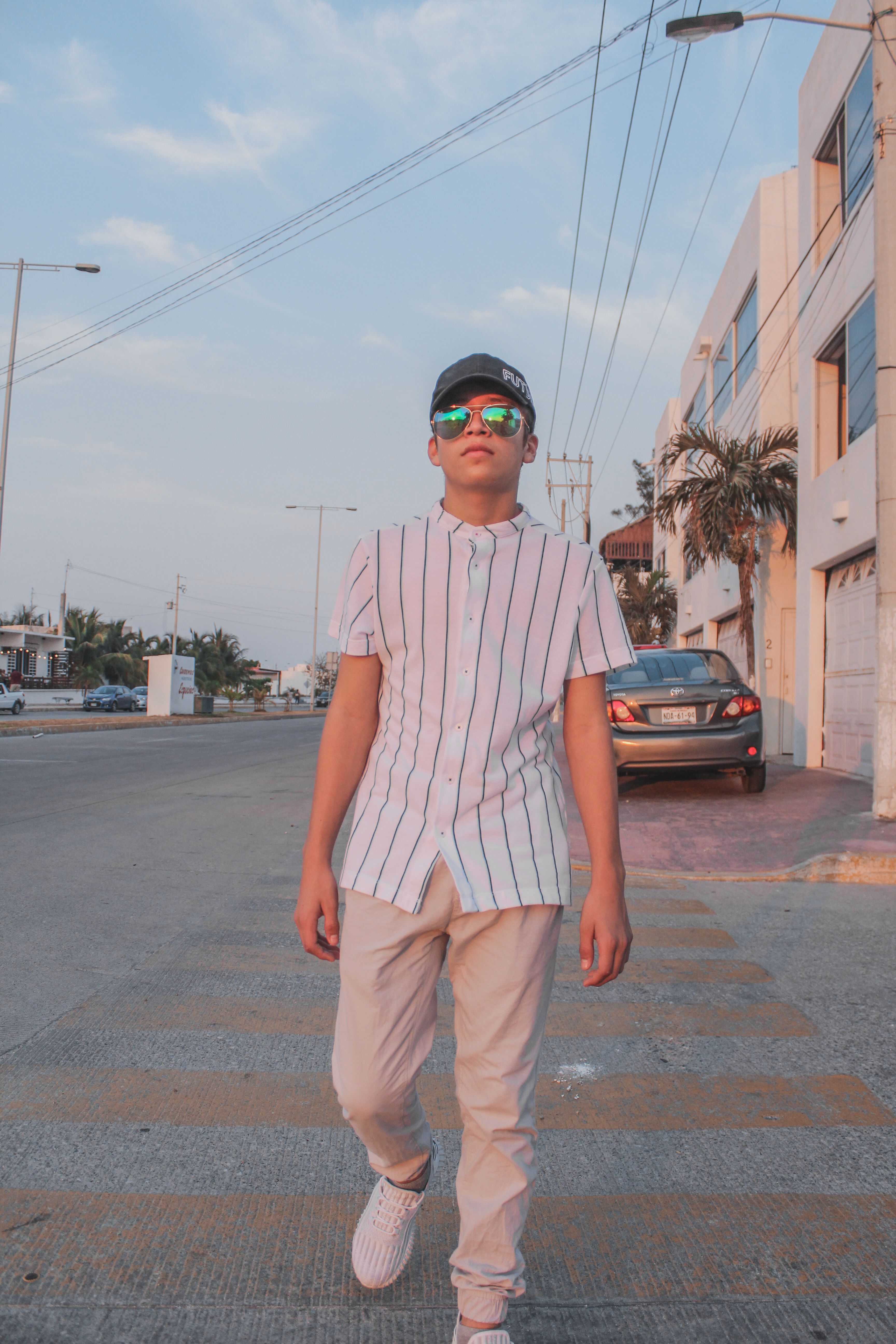 Casual young man with sunglasses strolling down a sunny urban street.