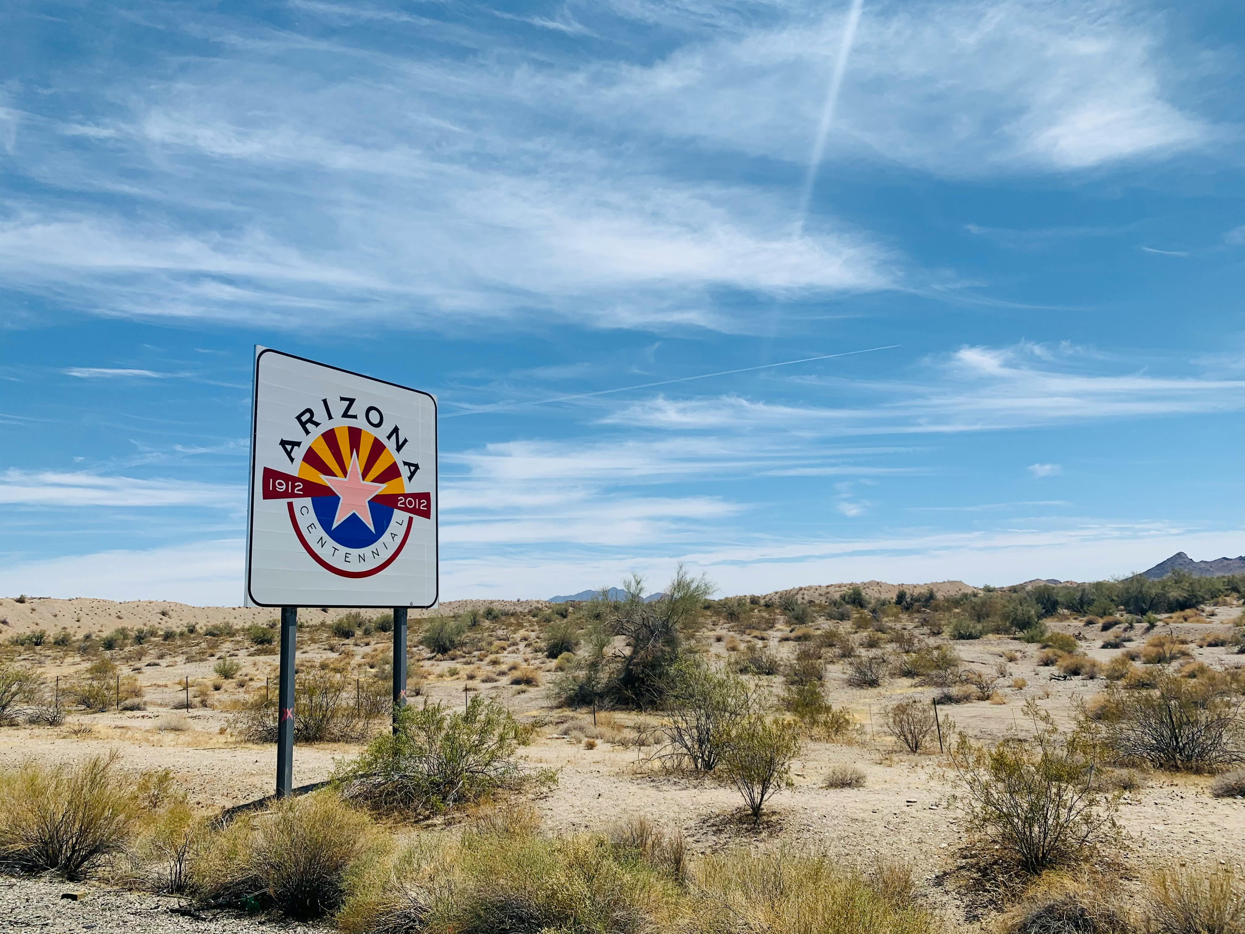 Desert landscape with Arizona Centennial sign and clear blue sky.