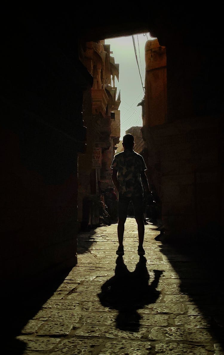 Man Standing In Gate Leading To Narrow Street