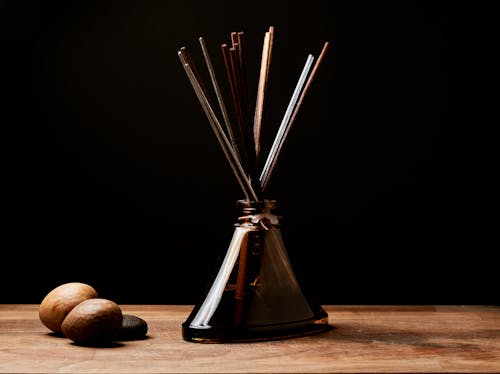 Close-Up Photo of Wood Incense Stick on a Brown Glass Bottle