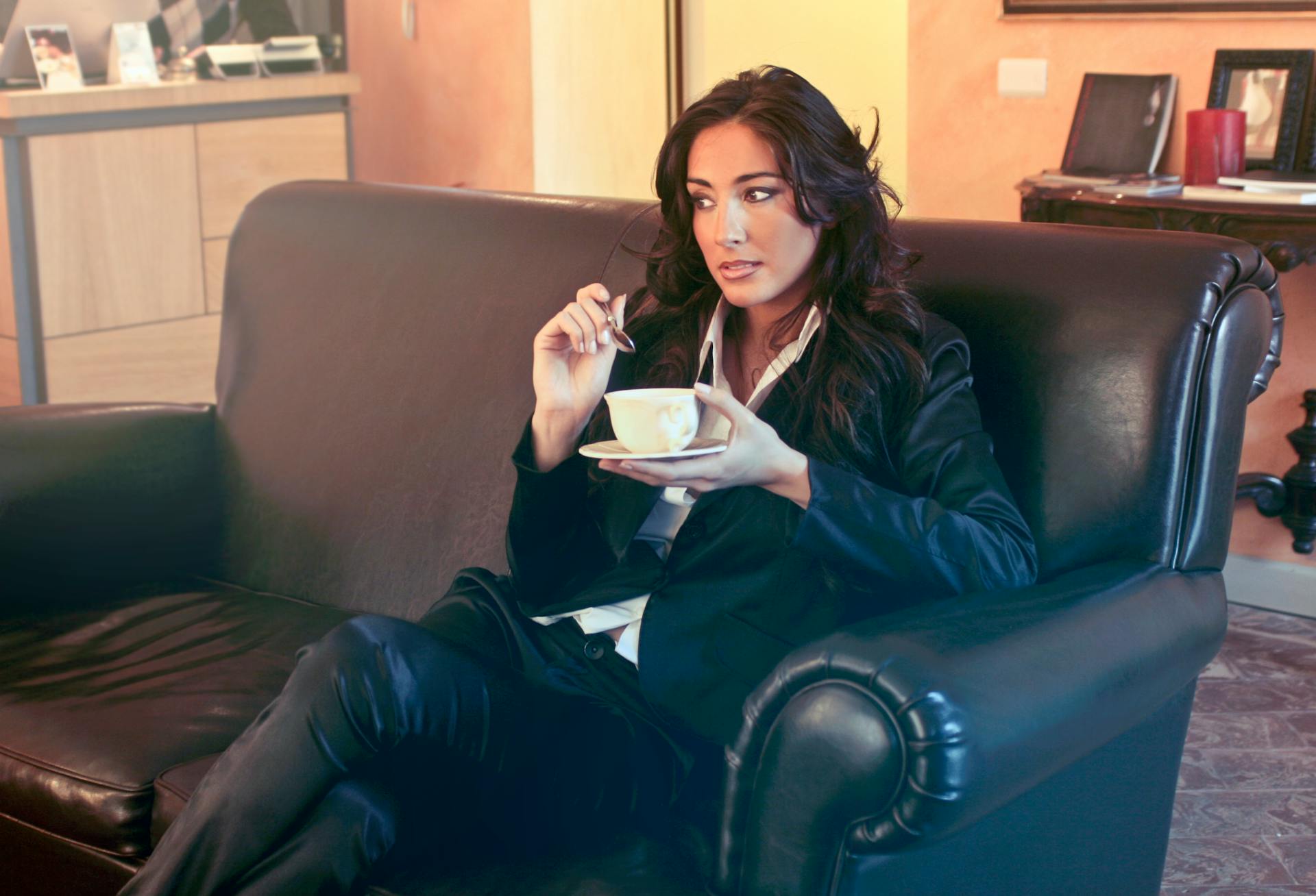 Stylish businesswoman enjoying a coffee break in a modern office lounge, conveying relaxation and elegance.