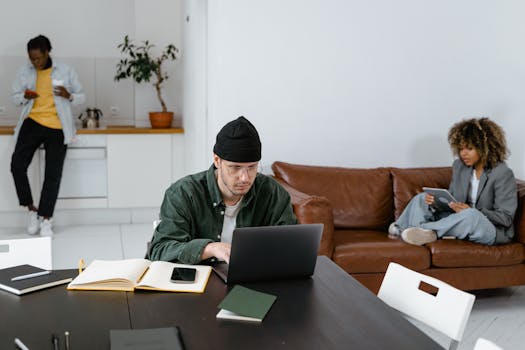 A diverse group of adults using laptops and tablets in a contemporary office space.