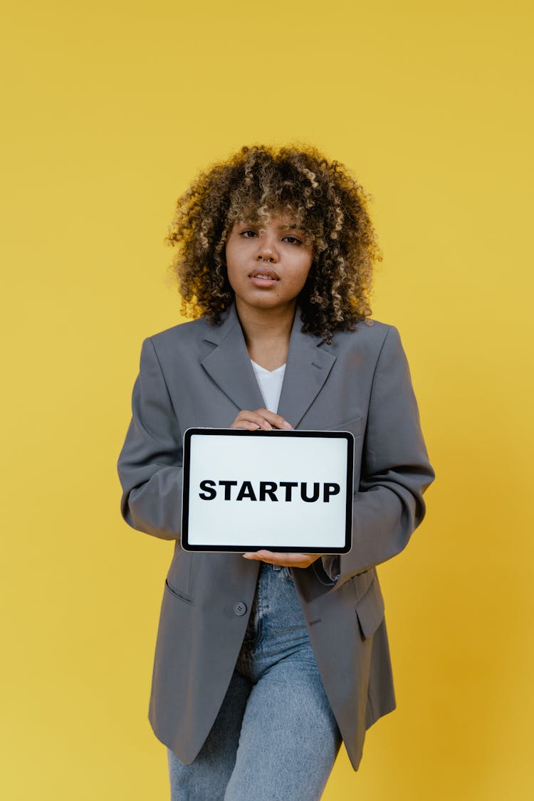 Woman In Gray Suit Holding A Tablet Computer Showing Startup Message