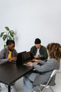 Diverse group of professionals working on laptops in a modern office setting, fostering teamwork.