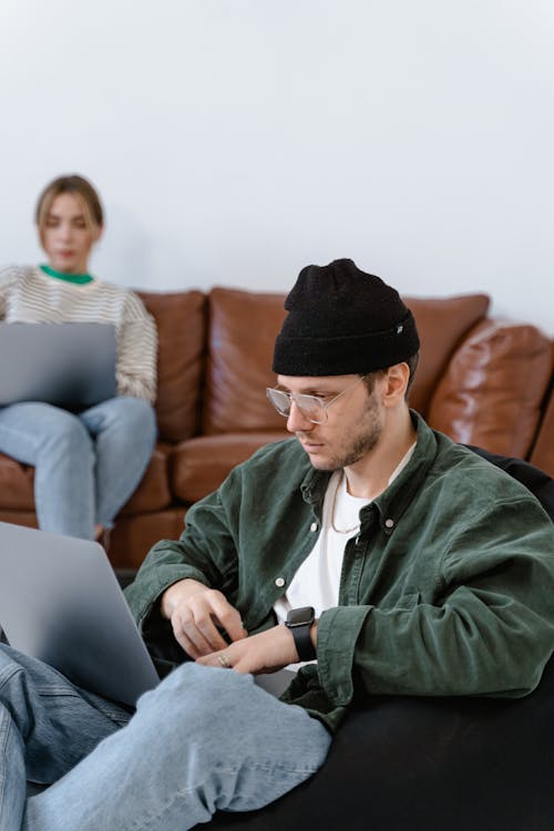 A Man Wearing Beanie Hat While Using Laptop