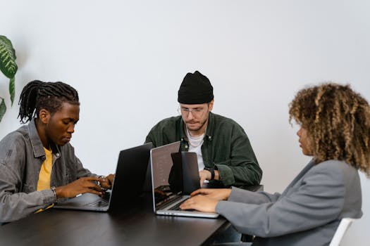A diverse group of professionals working together on laptops in a contemporary office environment.