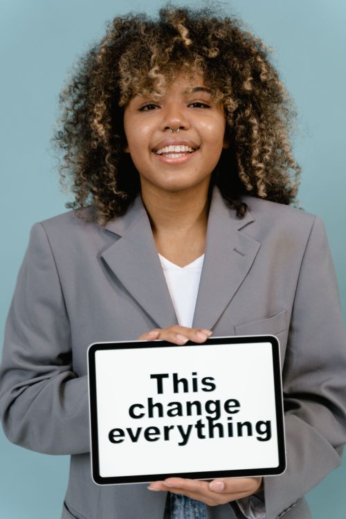 Free Smiling woman with afro hair holding a tablet displaying an inspiring message. Stock Photo